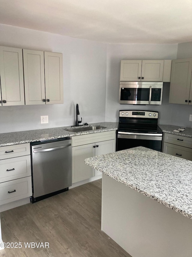 215 E 8th St, Watsontown, PA 17777 - kitchen featuring appliances with stainless steel finishes, a sink, wood finished floors, and light stone counters