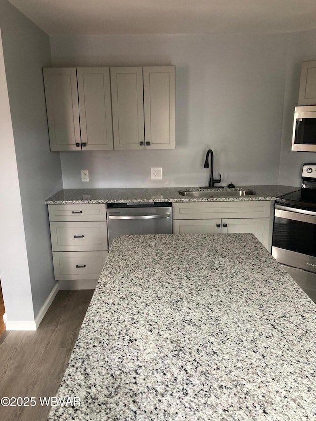 215 E 8th St, Watsontown, PA 17777 - kitchen with stainless steel appliances, a sink, dark wood finished floors, light stone countertops, and baseboards