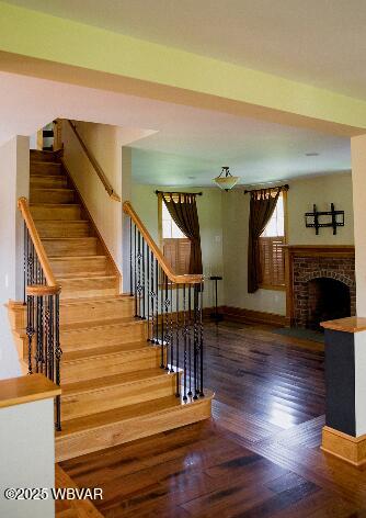 796 Ellis Artley Rd, Muncy, PA 17756 - staircase featuring wood finished floors, baseboards, and a brick fireplace