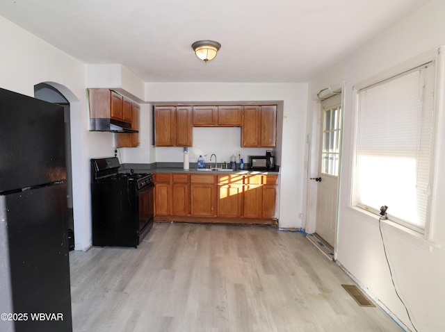 kitchen with black appliances, sink, and light hardwood / wood-style flooring