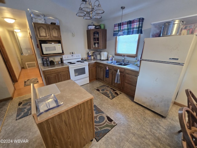 kitchen with white appliances, decorative light fixtures, a notable chandelier, and sink