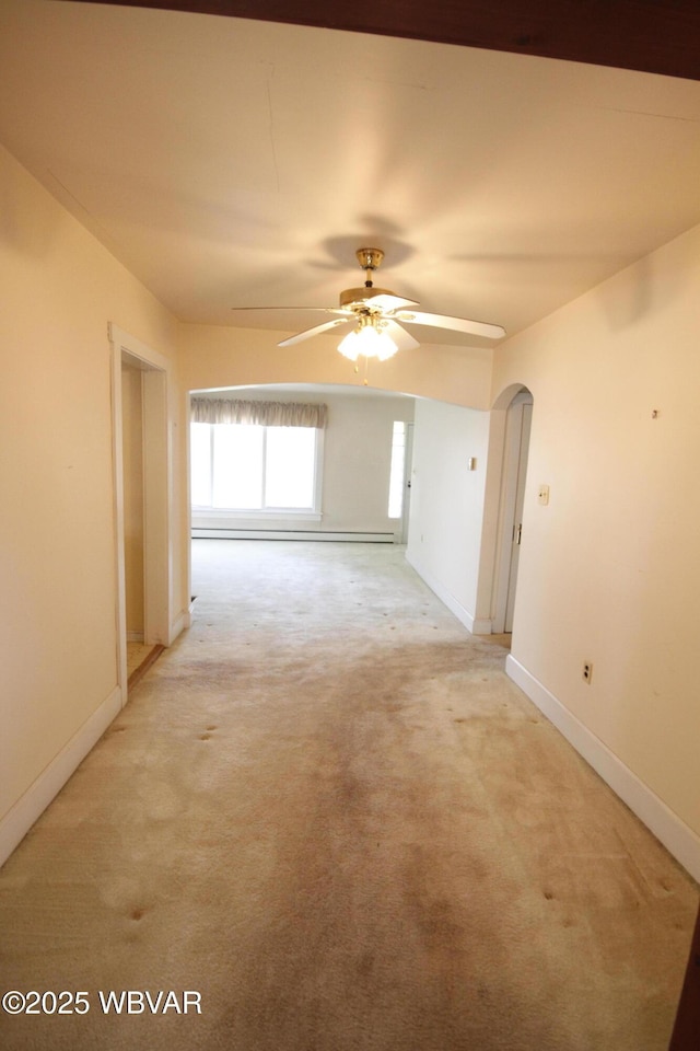 empty room with ceiling fan, light carpet, baseboards, and arched walkways