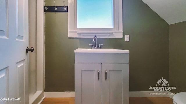 bathroom with vanity, toilet, and vaulted ceiling