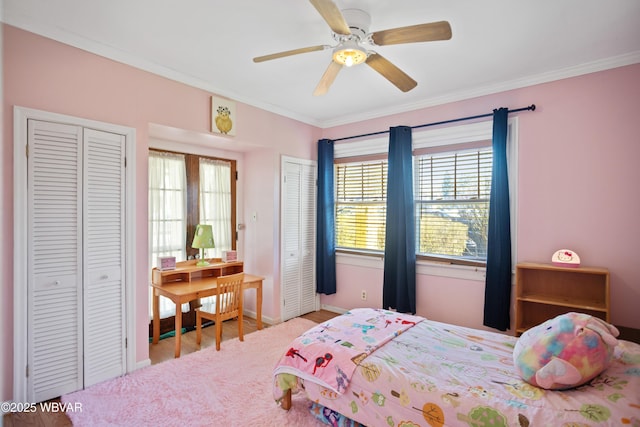 bedroom featuring crown molding, ceiling fan, wood finished floors, multiple closets, and baseboards
