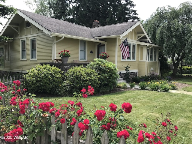view of front of home with roof with shingles, a chimney, fence, and a front lawn