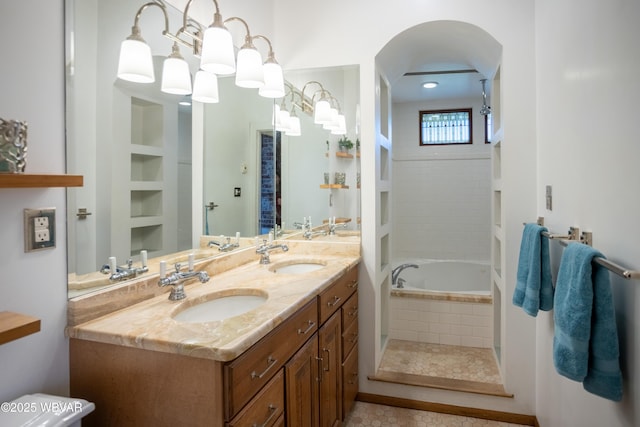 bathroom featuring double vanity, a relaxing tiled tub, and a sink