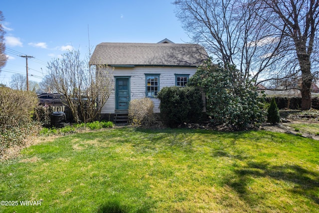 exterior space featuring entry steps, a front yard, and a shingled roof