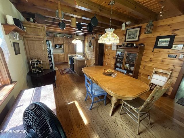 dining room featuring hardwood / wood-style floors, beamed ceiling, wooden ceiling, and wood walls