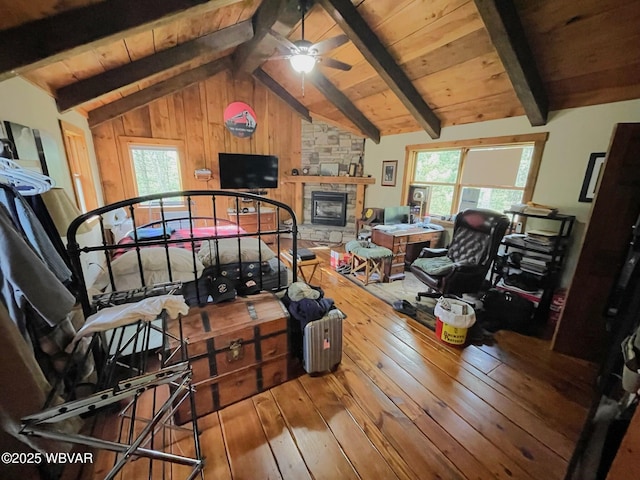 living area featuring hardwood / wood-style floors, a fireplace, a ceiling fan, wood ceiling, and wooden walls