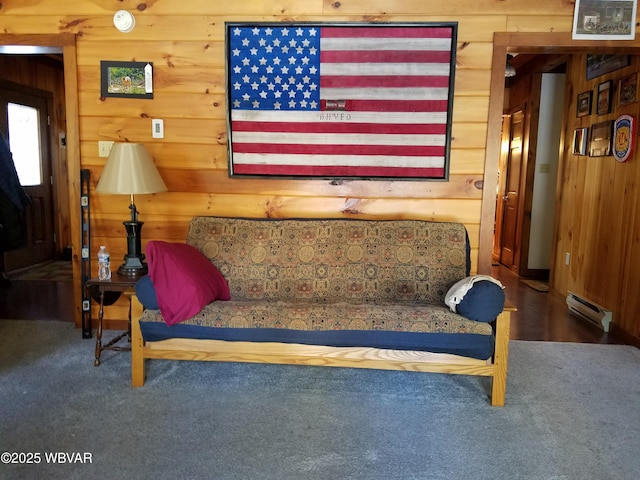 living area featuring carpet floors, wood walls, and a baseboard heating unit