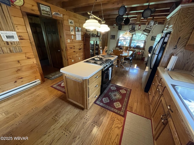 kitchen with black range with gas cooktop, light wood-type flooring, brown cabinets, light countertops, and a kitchen island