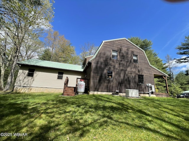 back of property featuring a lawn, cooling unit, a gambrel roof, and metal roof