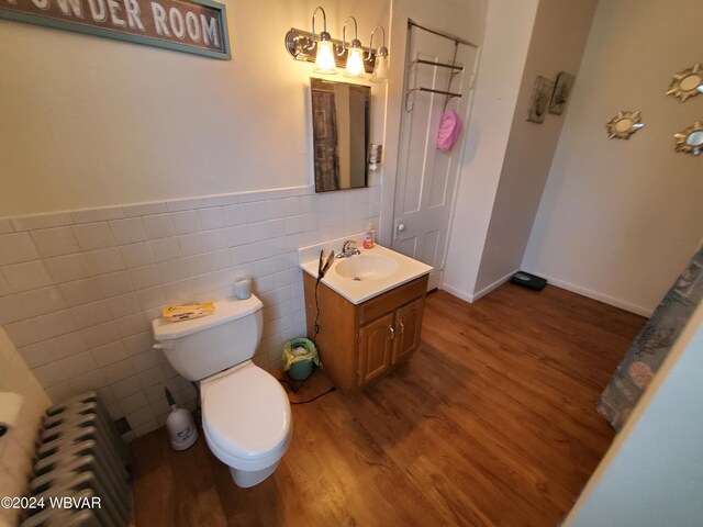 bathroom featuring vanity, wood-type flooring, tile walls, and radiator