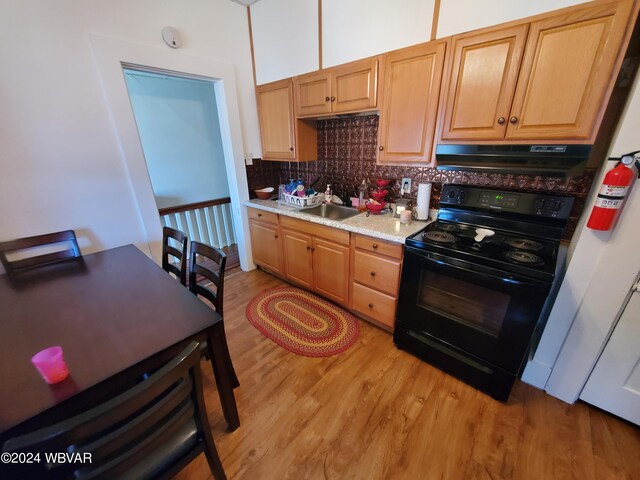 kitchen with backsplash, exhaust hood, black range with electric stovetop, sink, and light hardwood / wood-style floors