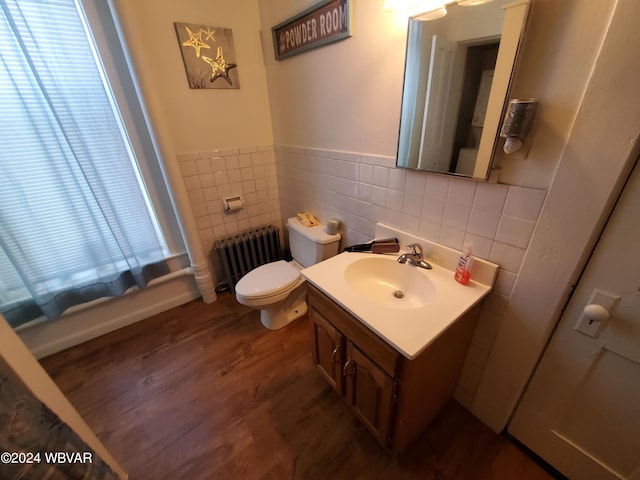 bathroom with vanity, hardwood / wood-style flooring, tile walls, radiator heating unit, and toilet