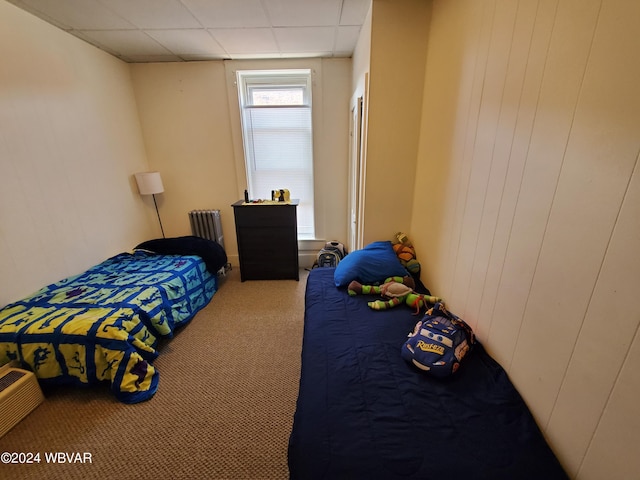 bedroom featuring a paneled ceiling, radiator heating unit, and carpet floors