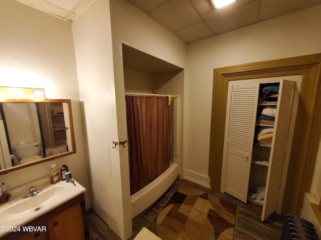 bathroom with radiator, a drop ceiling, wood-type flooring, toilet, and vanity