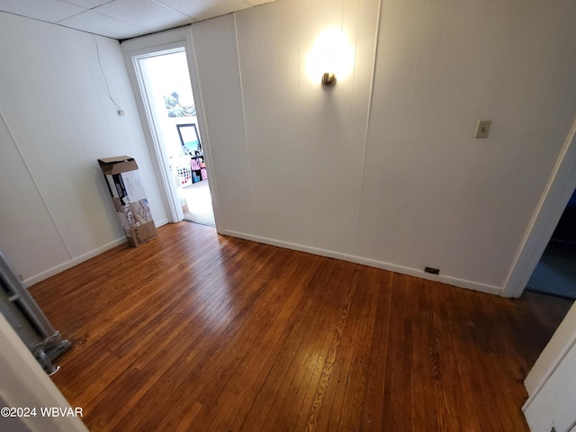 empty room featuring a drop ceiling and dark wood-type flooring