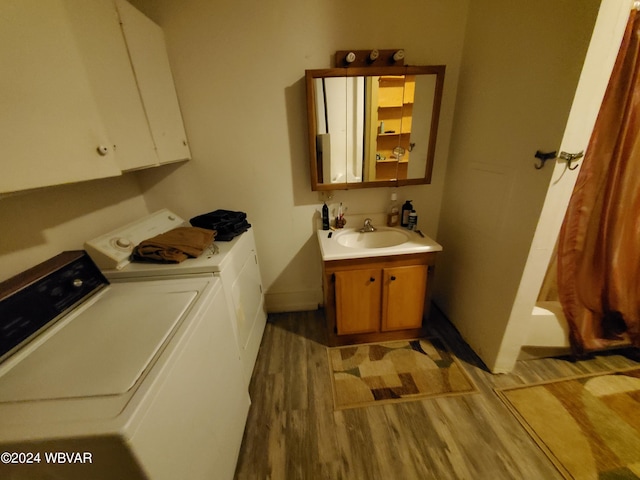 washroom with washing machine and clothes dryer, cabinets, sink, and light hardwood / wood-style floors