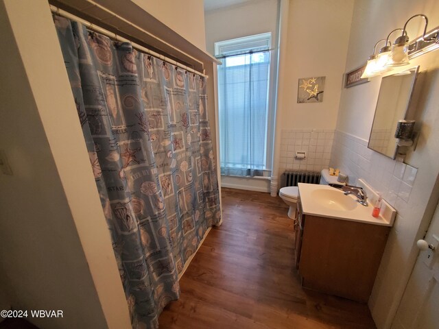 bathroom featuring radiator, toilet, vanity, tile walls, and hardwood / wood-style flooring