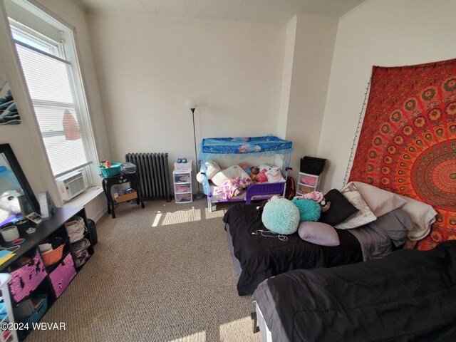 bedroom featuring light carpet and radiator heating unit