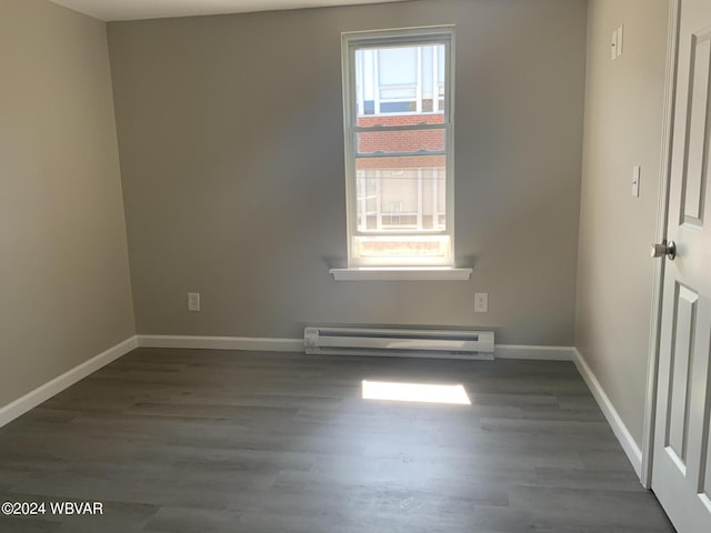 unfurnished room with plenty of natural light, dark hardwood / wood-style flooring, and a baseboard heating unit