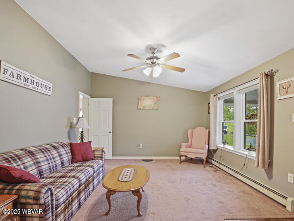 1498 Gainer Hill Rd, Dushore, PA 18614 - carpeted living room featuring a baseboard radiator, a ceiling fan, and lofted ceiling