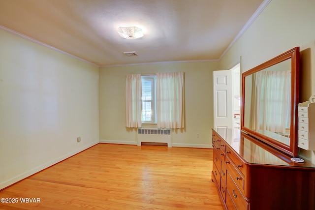 empty room featuring crown molding, light wood finished floors, radiator, baseboards, and visible vents