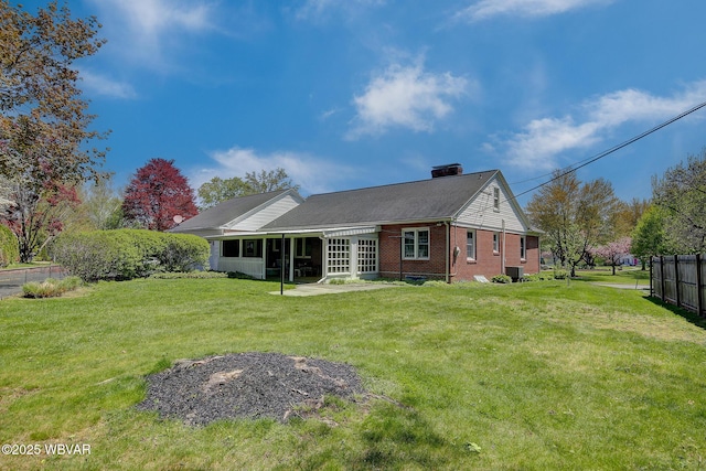 rear view of property featuring a chimney, brick siding, fence, a yard, and a patio