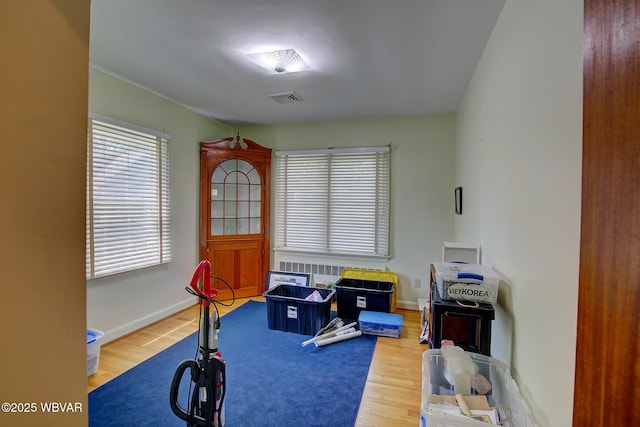 workout room featuring baseboards, wood finished floors, and visible vents