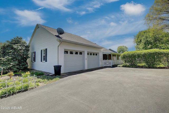 view of side of property featuring a garage, fence, and driveway