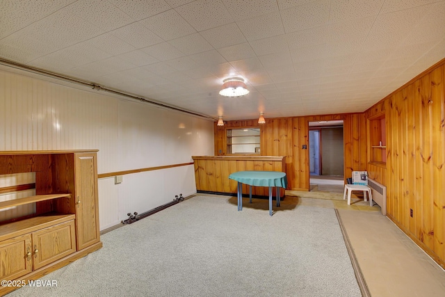 recreation room with light carpet and wood walls