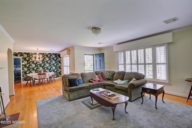 living room with visible vents, ornamental molding, light wood-style flooring, and an inviting chandelier
