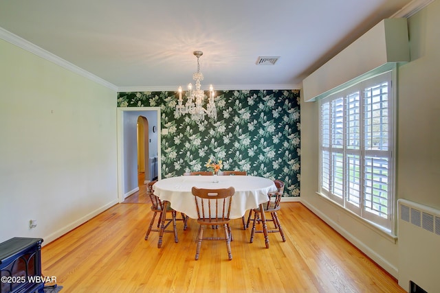 dining area featuring an inviting chandelier, radiator, wood finished floors, and visible vents