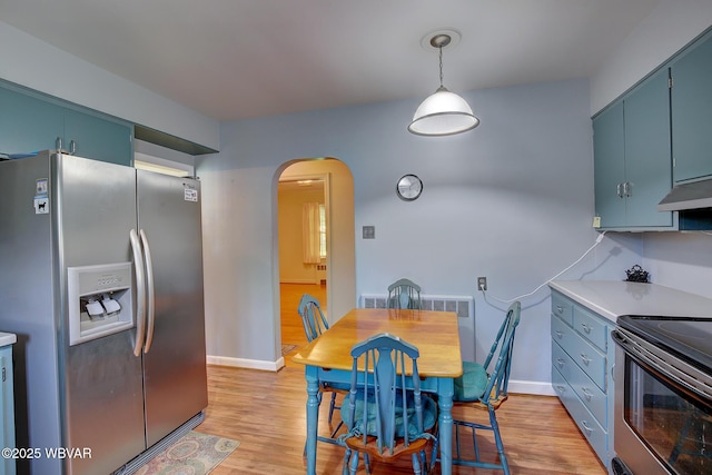 dining room with light wood-style floors, arched walkways, and baseboards