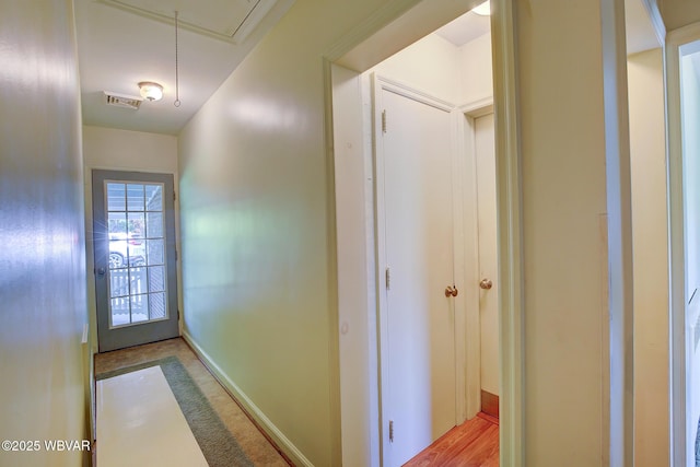 hallway featuring baseboards, visible vents, and attic access