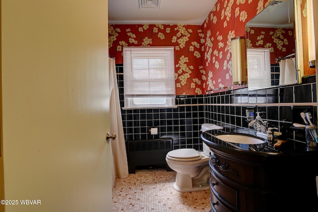 bathroom with visible vents, radiator, wainscoting, toilet, and wallpapered walls