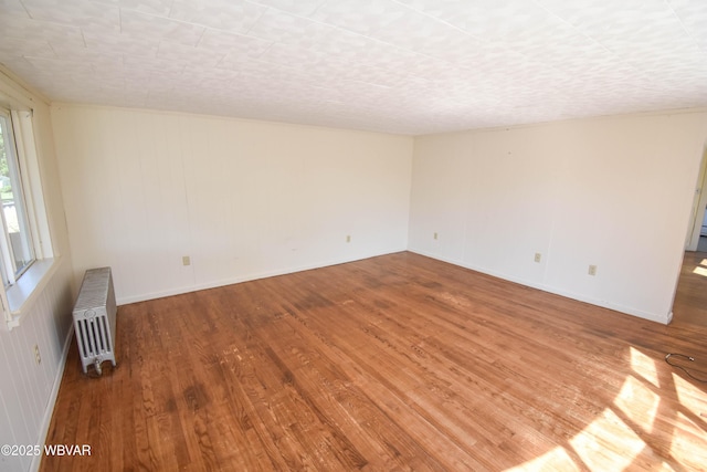 unfurnished room featuring radiator heating unit and wood-type flooring