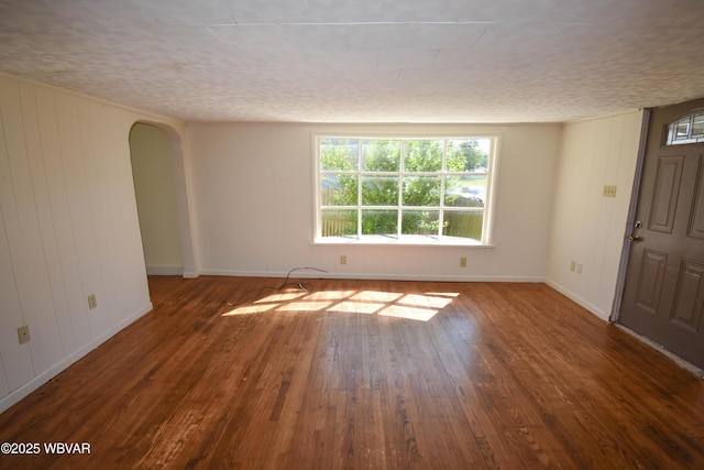 spare room with a textured ceiling and dark hardwood / wood-style floors