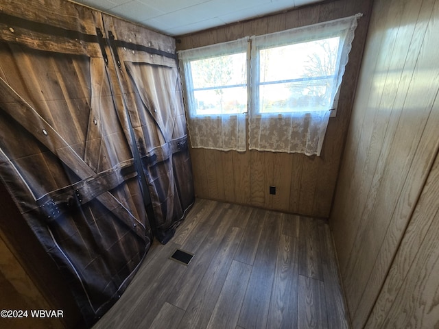 unfurnished room with dark hardwood / wood-style flooring and wood walls