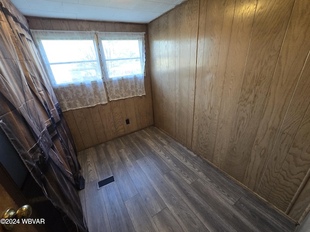 unfurnished room featuring dark hardwood / wood-style flooring, plenty of natural light, and wooden walls