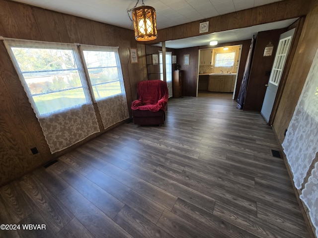 unfurnished room with a notable chandelier, dark hardwood / wood-style floors, sink, and wooden walls