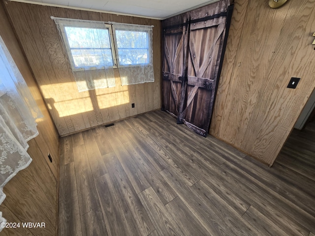 unfurnished room with dark hardwood / wood-style floors and wooden walls