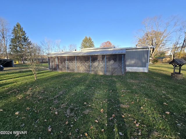 rear view of property featuring a lawn and an outdoor structure