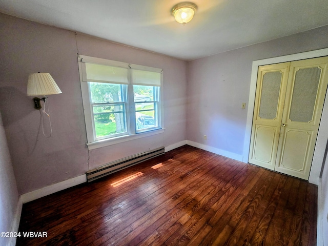 unfurnished bedroom featuring dark hardwood / wood-style floors, a closet, and a baseboard heating unit