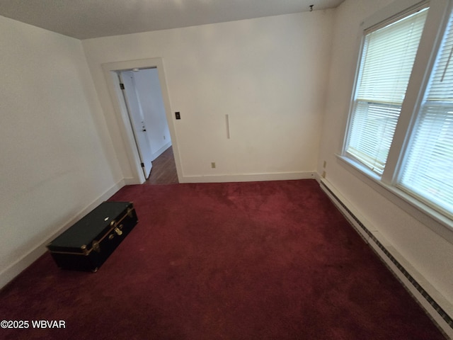 spare room featuring dark carpet and a baseboard heating unit