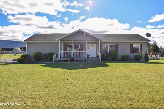 ranch-style home featuring covered porch and a front lawn