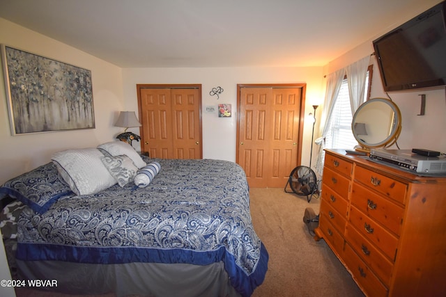 bedroom with light carpet and two closets