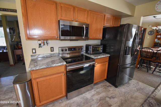 kitchen with light stone countertops, appliances with stainless steel finishes, and an inviting chandelier