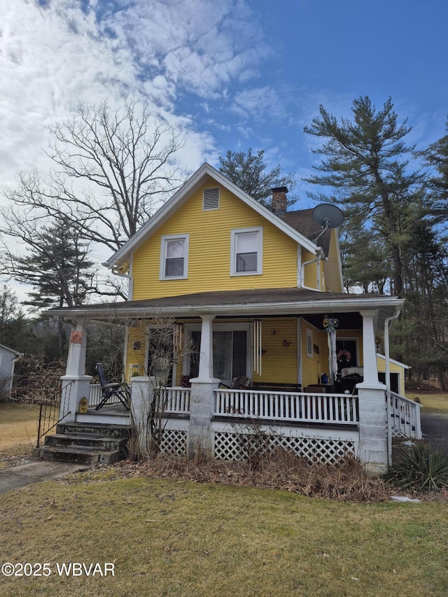 view of front facade with a front yard, covered porch, and a chimney